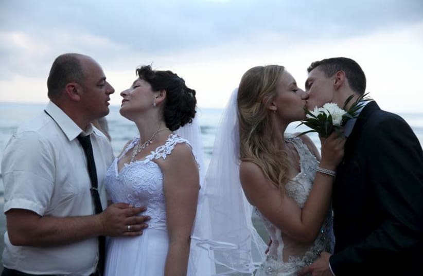 Couples kiss during a mass wedding at coastal city of Larnaca (photo credit: REUTERS/YIANNIS KOURTOGLOU)