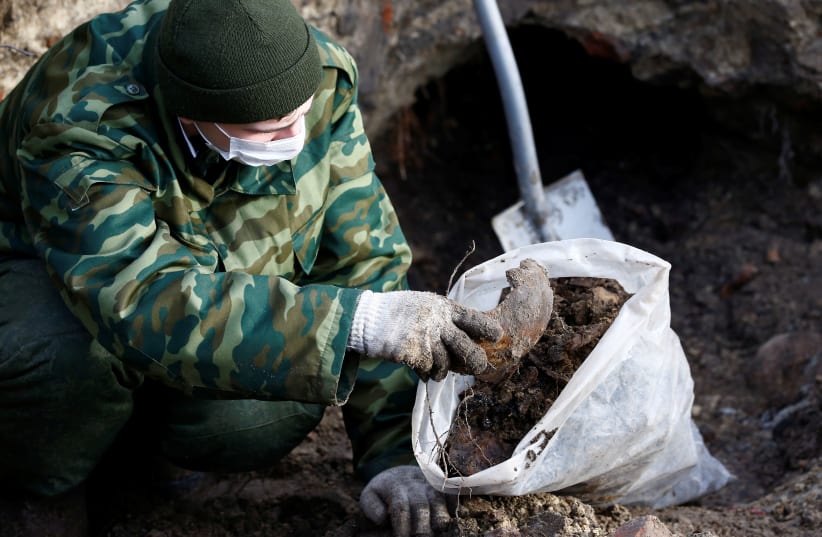 A soldier from a special "search battalion" of Belarus Defence Ministry takes part in the exhumation of a mass grave containing Jewish victims. Brest, Belarus February 2019. (photo credit: VASILY FEDOSENKO / REUTERS)