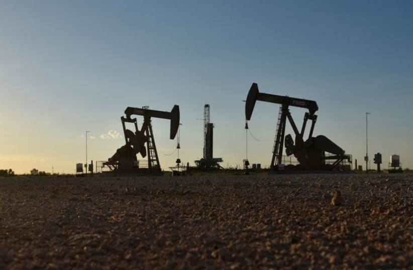 Pump jacks operate in front of a drilling rig in an oil field in Midland, Texas, in August (photo credit: REUTERS)