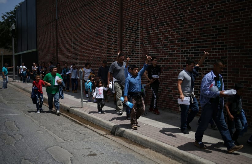 Undocumented immigrant families walk from a bus depot to a respite center after being released from detention in McAllen, Texas, U.S., July 28, 2018 (photo credit: LOREN ELLIOTT/REUTERS)
