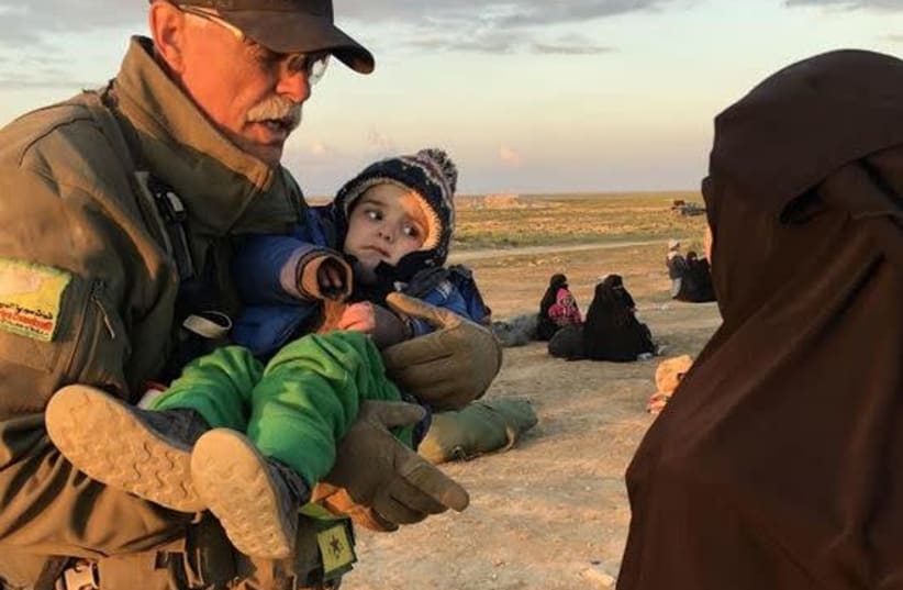 Paul Curtis Bradley carries a child near Baghuz  (photo credit: COURTESY FREE BURMA RANGERS)