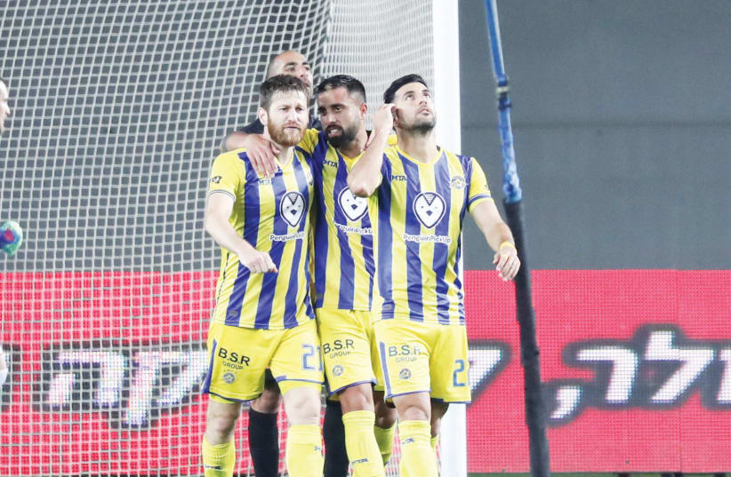 MACCABI TEL AVIV players celebrate after an 81st-minute goal by Avi Rikan (right), a tally which helped the yellow-and-blue complete a comeback from a 1-0 deficit and defeat Bnei Yehuda 2-1 on Monday night to close out the Premier League regular season.  (photo credit: DANNY MARON)