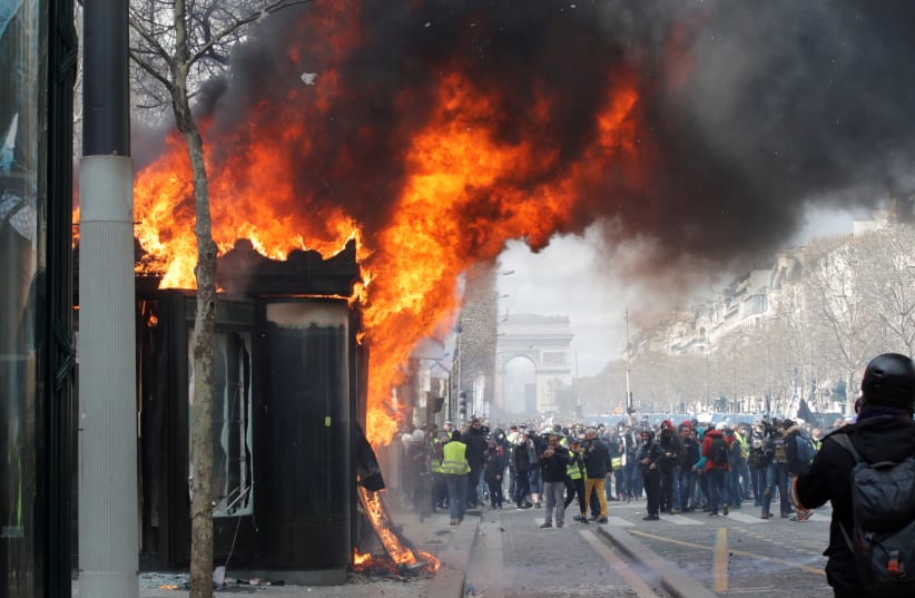 A burning newsagent's shop is seen during a demonstration by the "yellow vests" movement in Paris, France, March 16, 2019. (photo credit: PHILIPPE WOJAZER / REUTERS)