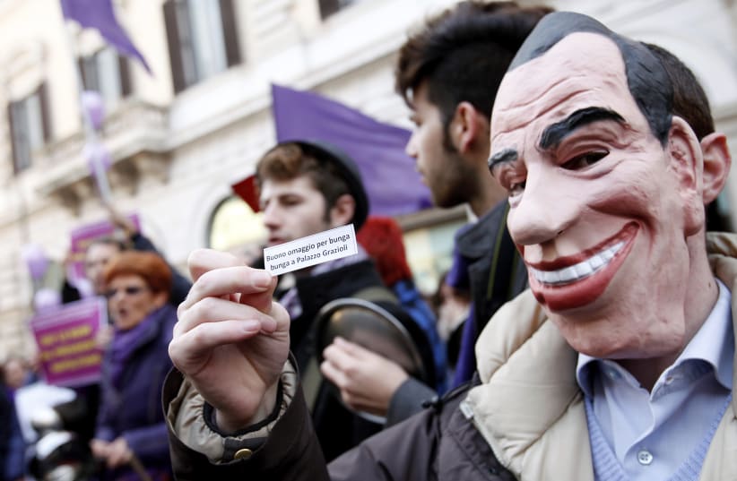 A protestor wearing a mask depicting Italian Prime Minister Silvio Berlusconi holds a paper during a demonstration calling for the resignation of Berlusconi in Rome February 12, 2011.  (photo credit: ALESSIA PIERDOMENICO / REUTERS)