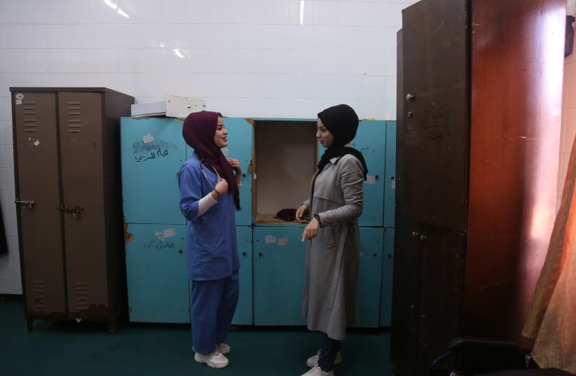 Palestinian midwife Sara Abu Taqea (L), 23, who works in the maternity ward at Gaza's Al-Ahli hospital, speaks with her colleague at the hospital in Gaza City, February 10, 2019.  (photo credit: REUTERS/SAMAR ABO ELOUF)