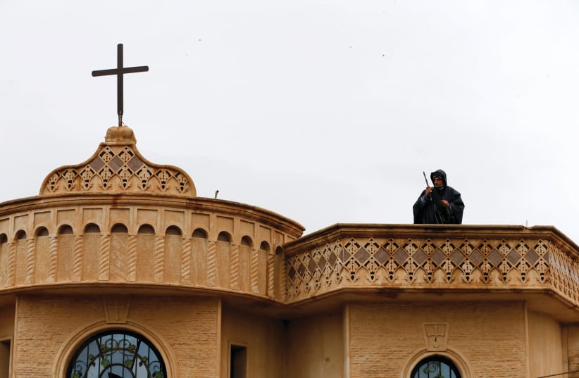 A SECURITY forces member stands atop a church in Bartella (photo credit: REUTERS)