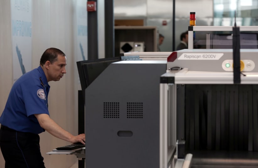 A Transport Security Administration employee scans baggage using new Automated Screening Lane technology (photo credit: JOE PENNEY)