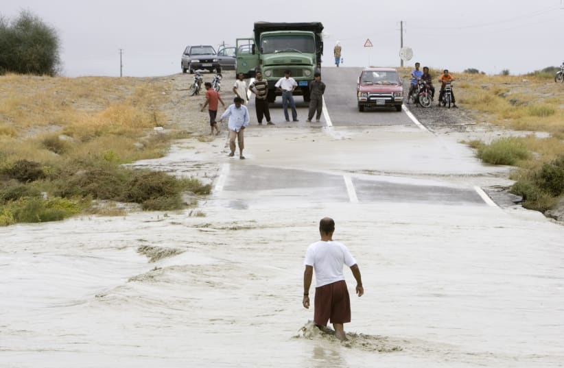 A man tries to cross a flooded road damaged by Cyclone Gonu near Jusk seaport, 2,000 km (1,240 miles) southeast of Tehran, June 8, 2007 (photo credit: REUTERS/MORTEZA NIKOUBAZL)