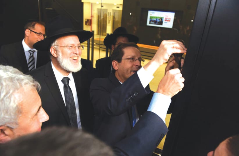 JEWISH AGENCY Chairman Isaac Herzog affixes a mezuzah on the restored AMIA building in Buenos Aires. (photo credit: Courtesy)