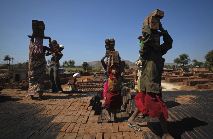 Girls carry bricks to be baked in a kiln at a brickyard on the outskirts of Karad in Satara district (photo credit: REUTERS)