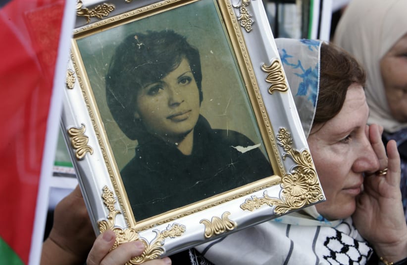 A woman holds a photo of Palestinian guerrilla Dalal al-Mughrabi as a convoy carrying her body passes by on Beirut's airport road July 17, 2008. The body of Mughrabi, who was killed while leading a 1978 raid into Israel, was handed over by Israel as part of a prisoner swap with Hezbollah. (photo credit: SHARIF KARIM / REUTERS)