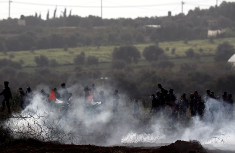 Palestinians protest next to the border fence between Israel and the Gaza Strip, as it is seen from its Israeli side March 30, 2019 (photo credit: AMIR COHEN/REUTERS)