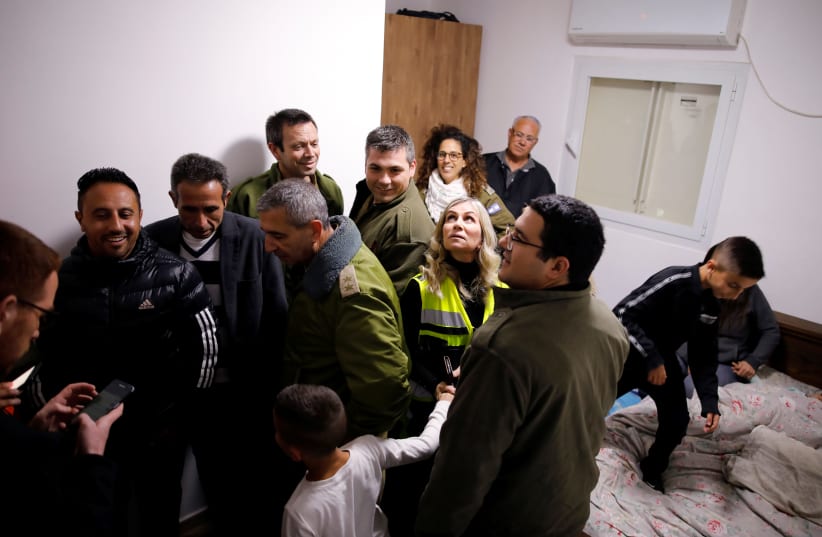 Residents and security personnel gather in a bomb shelter inside a house that was hit earlier, as air-raid siren goes off for incoming rockets from Gaza, in Sderot, Israel March 25, 2019 (photo credit: AMIR COHEN/REUTERS)