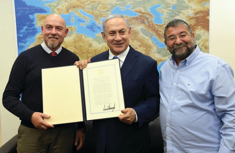 PRIME MINISTER Benjamin Netanyahu shows an executive order signed by US President Donald Trump to Katzrin Mayor Dimi Apartsev (left) and Golan Regional Council chairman Haim Rokah (photo credit: HAIM ZACH/GPO)