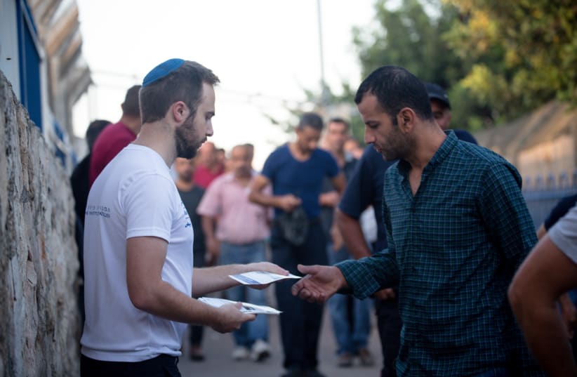 A representative for Blue & White Human Rights offering pamphlets to Palestinians (photo credit: COURTESY LAURA BEN-DAVID)