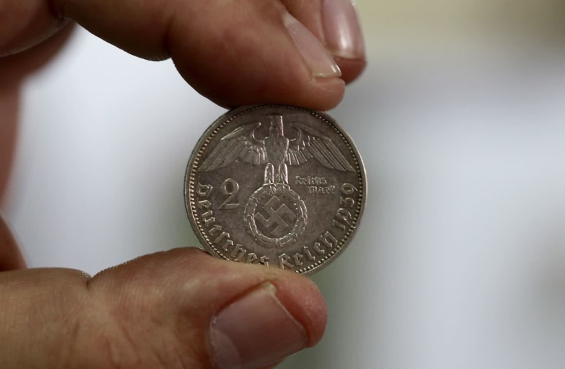 Minor Blanco, owner of a shop called "Caza de Tesoros" (Treasure Hunting), holds up a German coin from 1939 at his shop, in San Jose, Costa Rica September 23, 2015. The Los Angeles-based Simon Wiesenthal Center, which keeps tabs on anti-Semitism worldwide, sent Justice Minister Cecilia Sanchez Romer (photo credit: JUAN CARLOS ULATE / REUTERS)