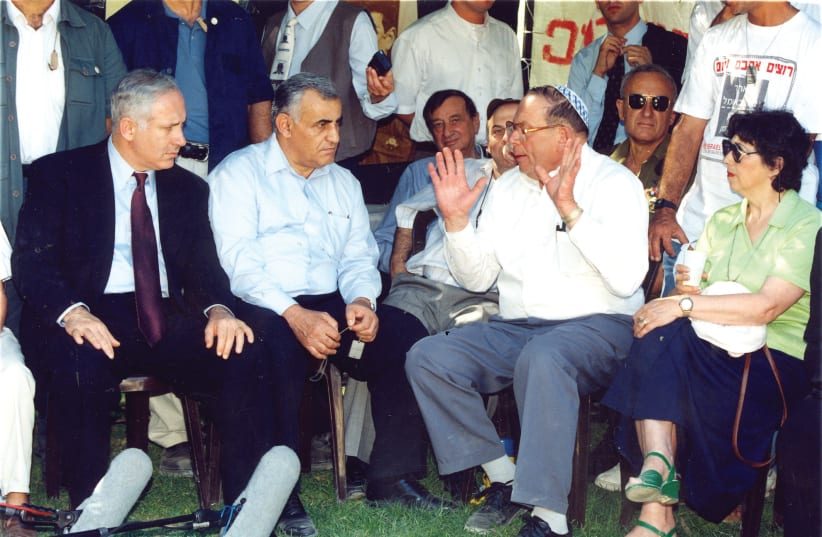 Prime Minister Benjamin Netanyahu and then-defense minister Yitzhak Mordechai listen to Yona Baumel (gesturing) as Baumel's wife, Miriam, (right) looks on, in 1997 (photo credit: BRIAN HENDLER)