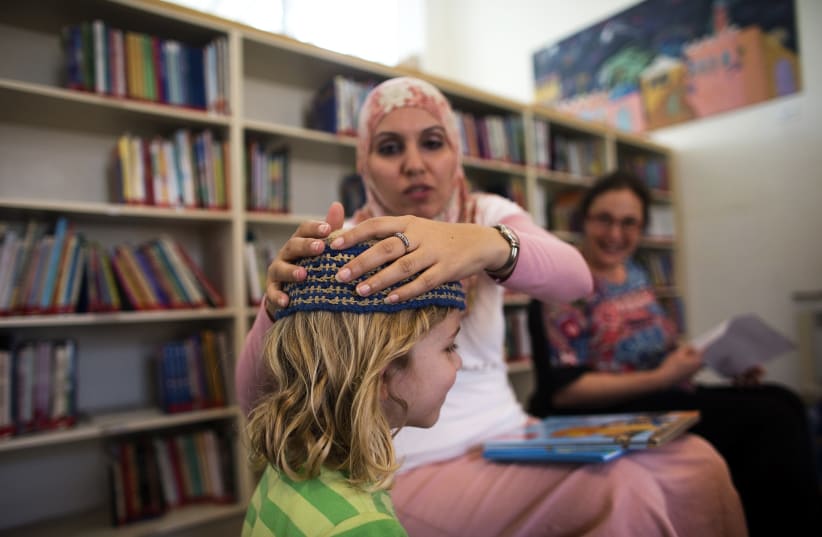 Alia Tunisi adjusts the skullcap of a student, Hand in Hand Arab Jewish bilingual school, Jerusalem, 2014. (photo credit: RONEN ZVULUN/REUTERS)