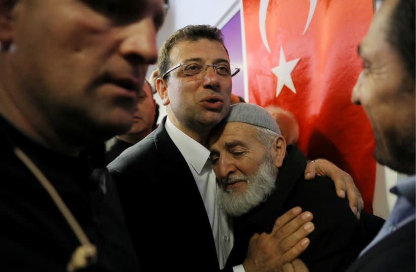 Ekrem Imamoglu, main opposition Republican People's Party (CHP) candidate for mayor of Istanbul, embraces his supporter at his election campaign office in Istanbul, Turkey April 1, 2019. (photo credit: HUSEYIN ALDEMIR/REUTERS)