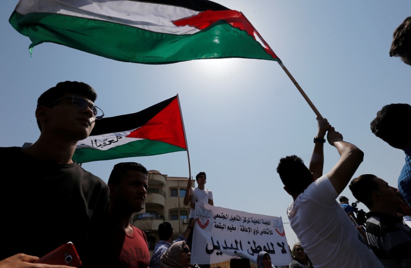 Palestinian refugees hold Palestinian flags and chant slogans during a protest in front of UNRWA office in Amman, September 2, 2018.  (photo credit: MUHAMMAD HAMED / REUTERS)