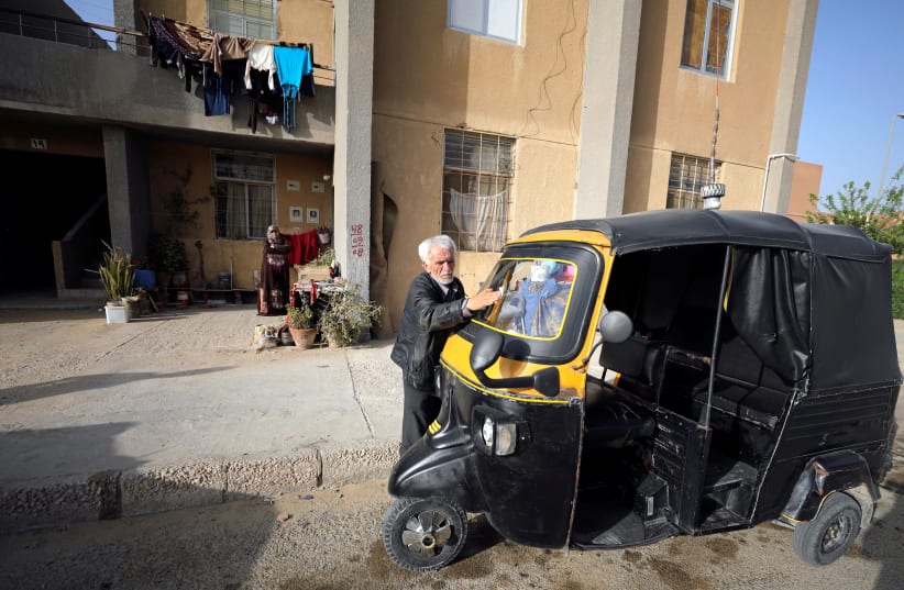 Syrian refugee Ahmad al-Khatib cleans his auto rickshaw as his wife Ilham Mohammad watches, outside their home in Cairo, Egypt April 8, 2019 (photo credit: MOHAMED ABD EL GHANY/REUTERS)