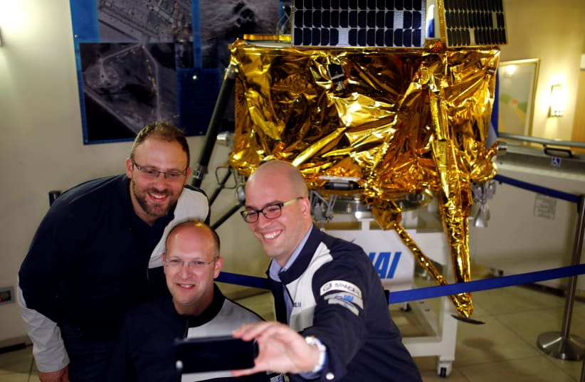 SpaceIL co-founders Kfir Damari (L), Yonatan Weintraub (C) and Yariv Bash (R) take a selfie in front of a model of the Beresheet spacecraft, near the control room, in Yahud, Israel, April 11, 2019 (photo credit: AMIR COHEN/REUTERS)