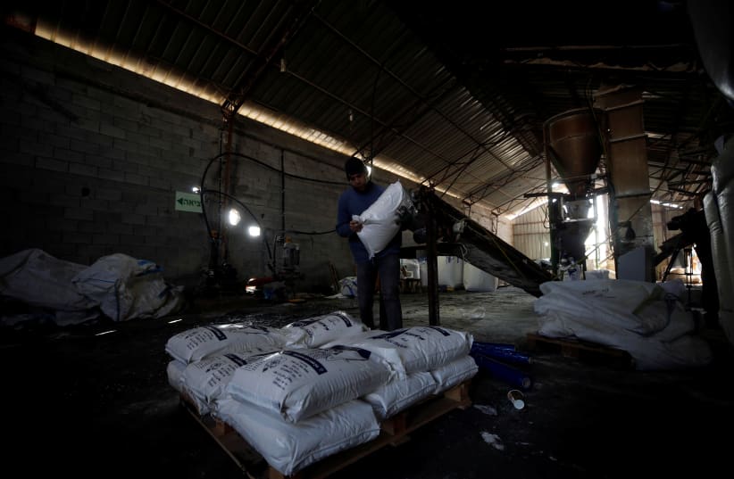 Palestinian worker carries a bag of salt at a factory near Jericho, West Bank, 2018.  (photo credit: REUTERS/MOHAMAD TOROKMAN)