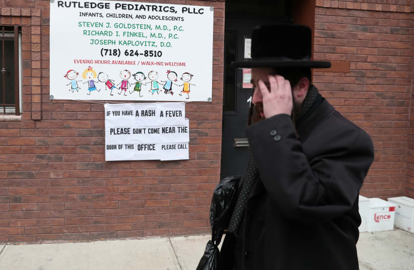 A sign warning people of measles in the ultra-Orthodox Jewish community of Williamsburg, two days after New York City Mayor Bill de Blasio declared a public health emergency in parts of Brooklyn in response to a measles outbreak, is seen in New York, U.S., April 11, 2019 (photo credit: SHANNON STAPLETON / REUTERS)