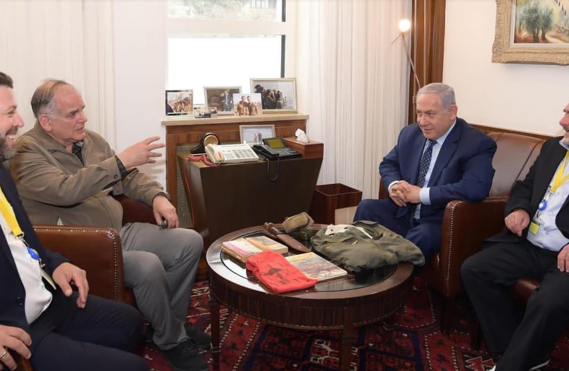 Ido Netanyahu [second from left] and Prime Minister Benjamin Netanyahu [second from right] accept personal items that used to belong to their late brother Yonatan Netanyahu from a former soldier of the late Netanyahu Yosef Shemesh [right]. (photo credit: AMOS BEN-GERSHOM/GPO)