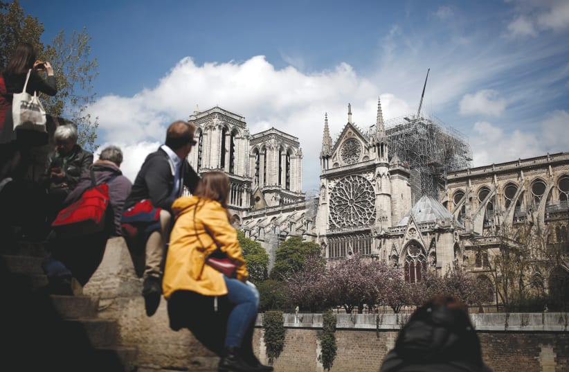 PEOPLE GAZE at the Notre-Dame Cathedral in Paris two days after a massive fire devastated large parts of the gothic structure (photo credit: REUTERS/BENOIT TESSIER)