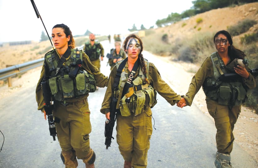 Women in an IDF combat unit help one of their fellow fighters during a training exercise (photo credit: REUTERS)