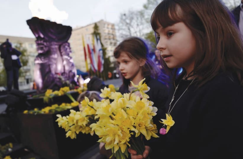 Polish children holding flowers near the Monument to the Ghetto Heroes (photo credit: KACPER PEMPEL / REUTERS)
