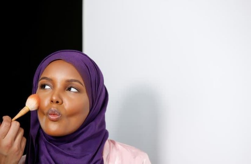 Fashion model and former refugee Halima Aden, who is breaking boundaries as the first hijab wearing model gracing magazine covers and walking in high profile runway shows has her makeup applied during a shoot at a studio in New York City, U.S .August 28, 2017. Photo taken August 28, 2017. (photo credit: BRENDAN MCDERMID/REUTERS)