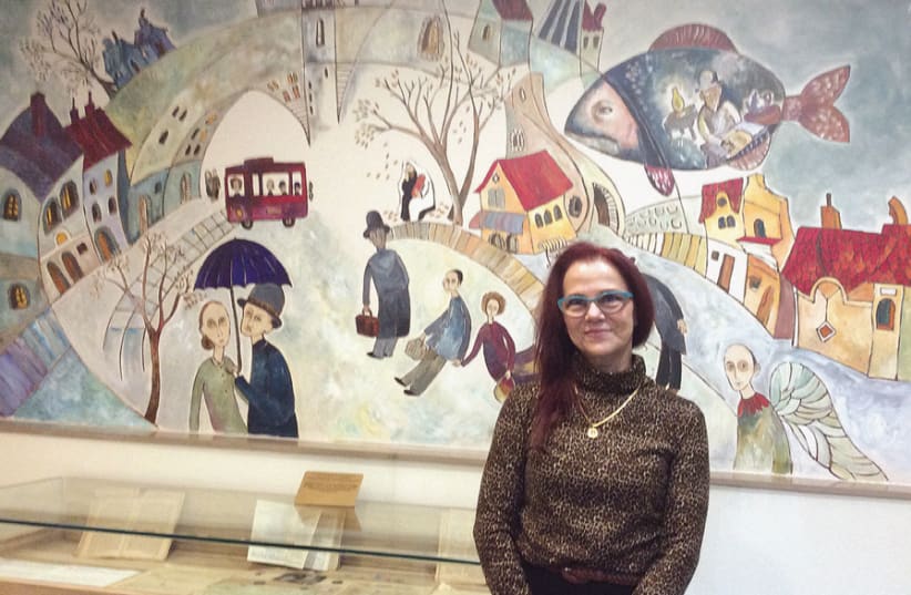 Museum director Claudia Sophia-Weinberg with her mural of a pre-war Polish village (photo credit: WENDY BLUMFIELD)
