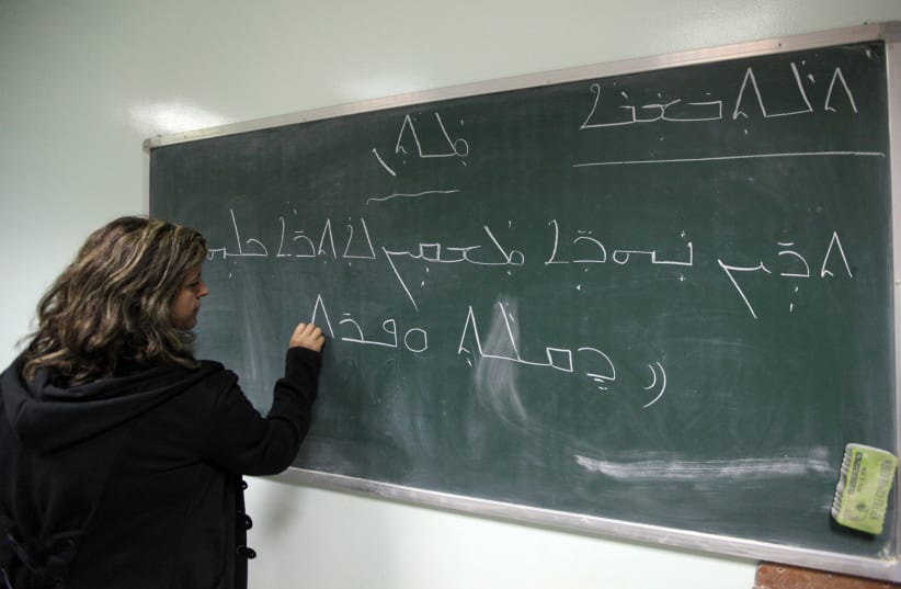A teacher writes on the blackboard during a Syriac language class in Baghdad November 20, 2012. (photo credit: SAAD SHALASH/REUTERS)