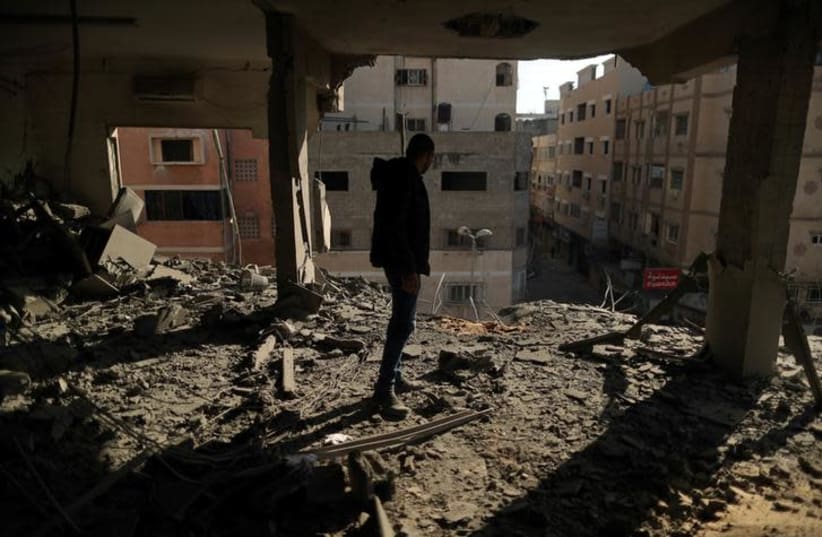A Palestinian man inspects a building destroyed in Israeli air strikes, in Gaza City (photo credit: REUTERS/SUHAIB SALEM)