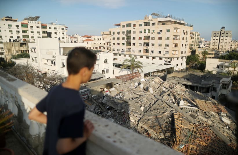 A Palestinian boy looks at the remains of a building that was destroyed in Israeli air strikes, in Gaza City May 5, 2019 (photo credit: SUHAIB SALEM / REUTERS)