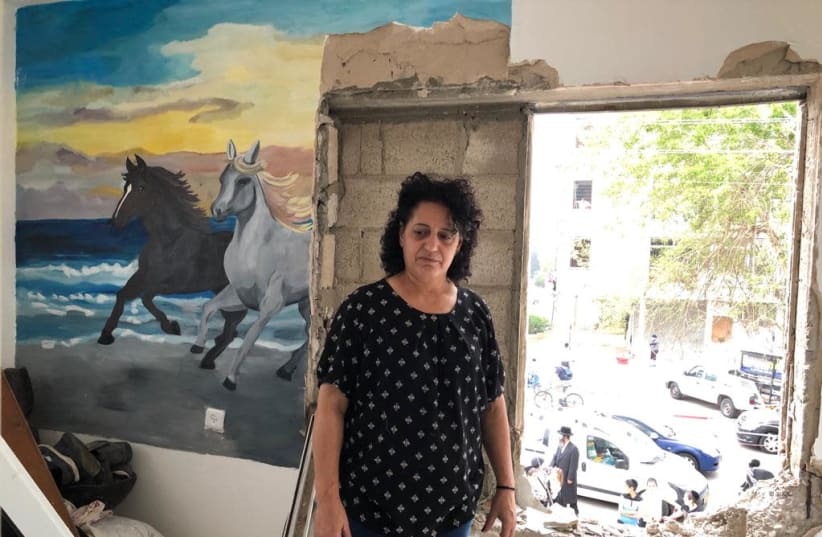 MIRIAM GOTTLIEB stands next to a blown out window and section of a wall in her building, destroyed in Sunday’s rocket attack against Ashdod. (photo credit: TOVAH LAZAROFF)