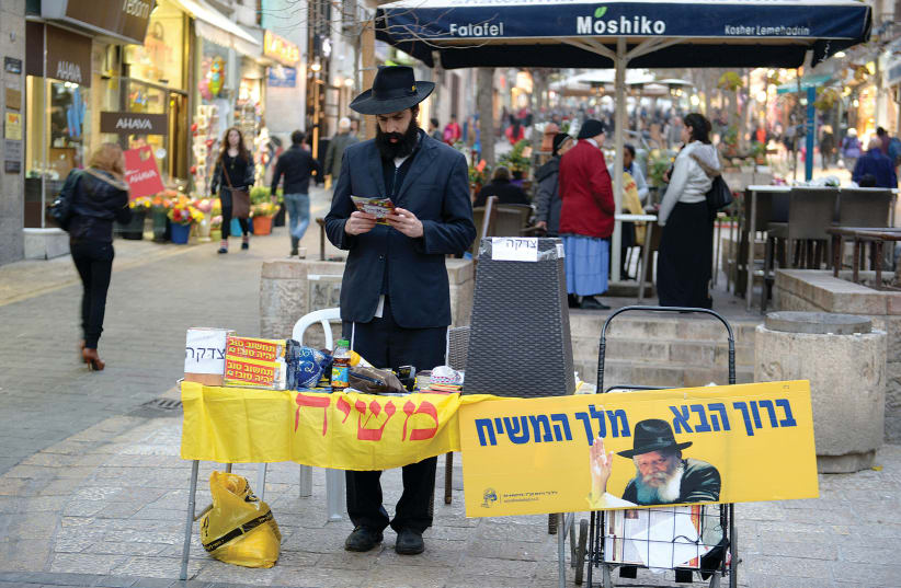 : A MEMBER of the Chabad community waits at a tefillin stand in Jerusalem (photo credit: MOSHE MILNER / GPO)