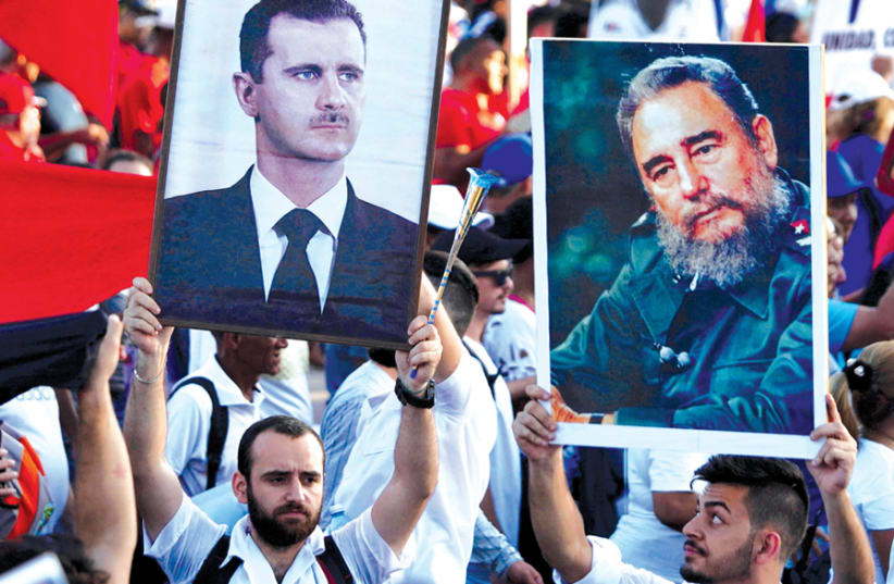 IMAGES OF Syrian President Bashar Assad and late Cuban president Fidel Castro are held aloft during a May Day rally in Havana on May 1 (photo credit: REUTERS)