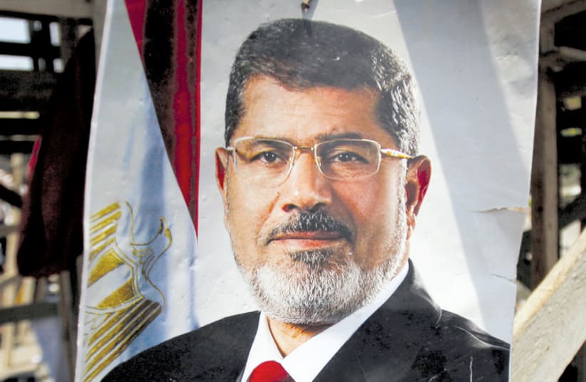 A POSTER of then-Egyptian president Mohamed Mursi reading ‘No substitute for the legitimacy’ is seen after night clashes with anti-Mursi forces in Giza, on the outskirts of Cairo, on July 3, 2013. (photo credit: REUTERS)