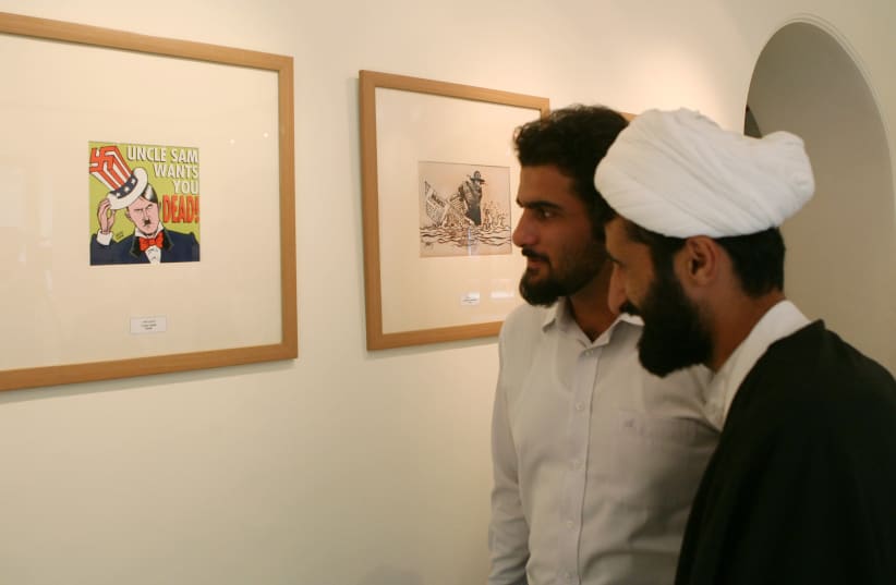 Iranian men look at a cartoon exhibit during the " in Tehran August 14, 2006 (photo credit: RAHEB HOMAVANDI/REUTERS)