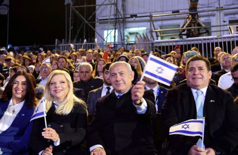 Prime Minister Benjamin Netanyahu [C] and Sara Netanyahu [L] waving Israeli flags during Independence Day  (photo credit: AMOS BEN-GERSHOM/GPO)