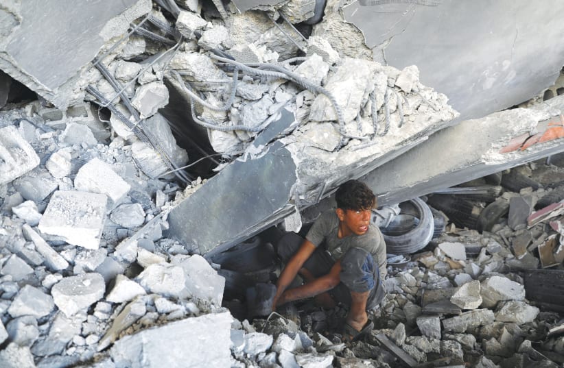A GAZA CITY resident searches for his belongings under the rubble of a building that was destroyed during air strikes by Israel. (photo credit: MOHAMMED SALEM/REUTERS)