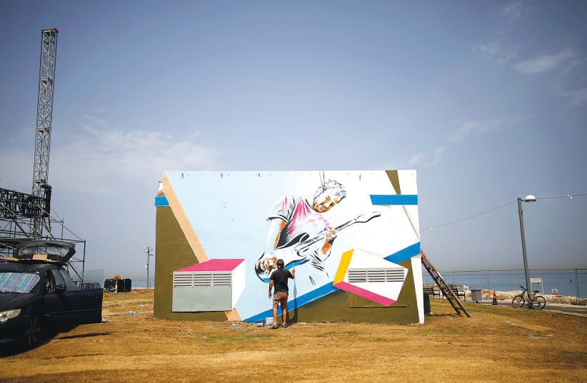 A MAN PAINTS a mural on a structure located close to the Eurovision Village in Tel Aviv (photo credit: REUTERS/CORINNA KERN)