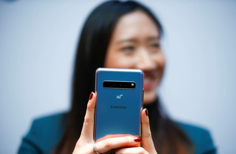 A Samsung employee poses with the new Samsung Galaxy S10 5G smartphone at a press event in London, Britain February 20, 2019. (photo credit: HENRY NICHOLLS/REUTERS)