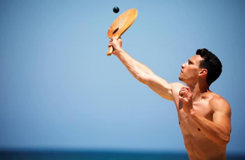 A man plays paddle ball, known in Hebrew as "matkot", a popular Israeli sport, at a beach in Ashkelon, Israel May 4, 2019. Picture taken May 4, 2019.  (photo credit: AMIR COHEN)