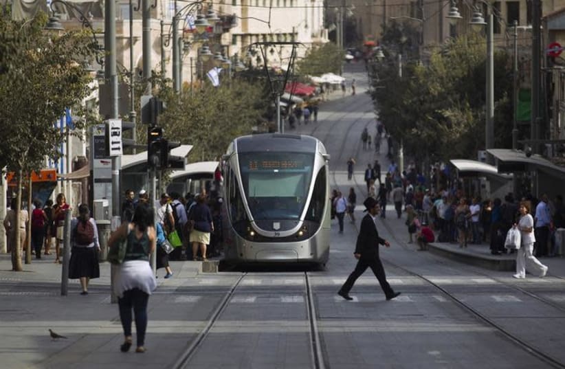 People walk near the light rail in the centre of Jerusalem (photo credit: REUTERS/AMIR COHEN)