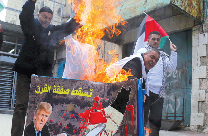 PALESTINIAN DEMONSTRATORS burn a poster depicting US President Donald Trump, in Hebron on February 22. (photo credit: REUTERS)