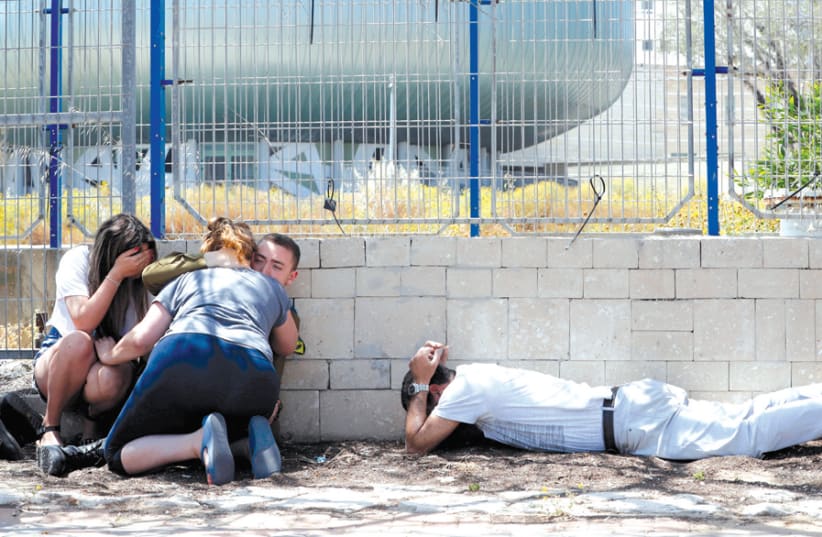PEOPLE TAKE cover as they hear sirens warning of incoming rockets from Gaza, in Ashkelon on May 5. (photo credit: REUTERS)